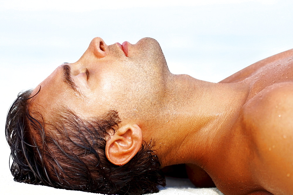Profile of young guy lying on the beach
