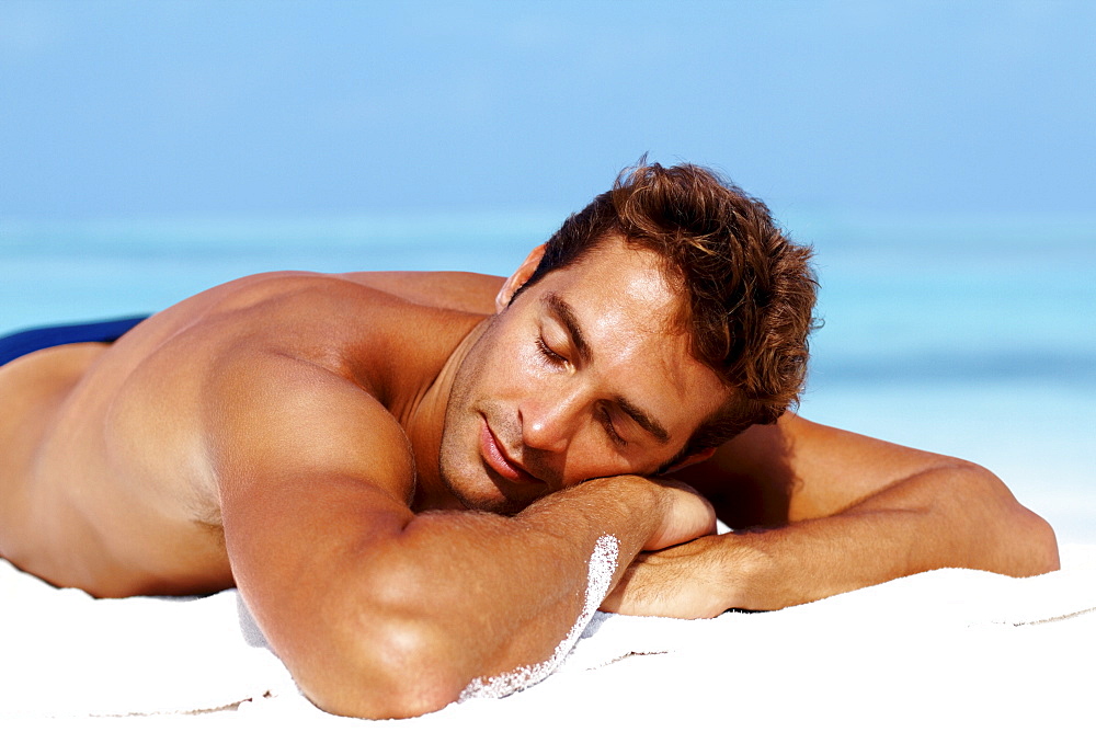 Handsome man taking sunbath at the beach