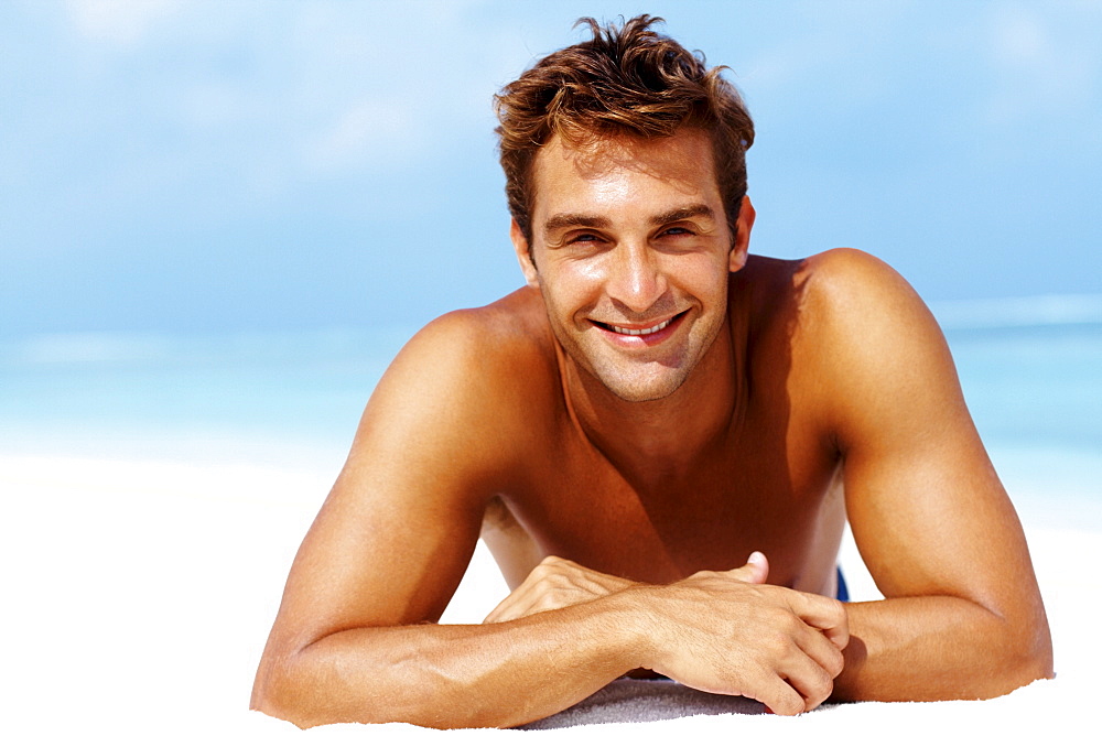 Happy young man lying at the beach