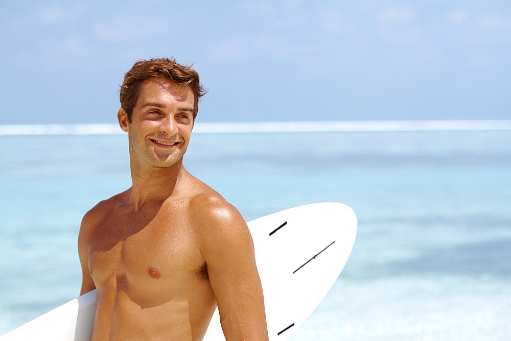 Shirtless young man holding surfboard