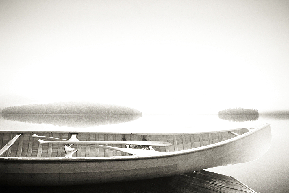 Wood canoe on dock on Lake Placid, black and white