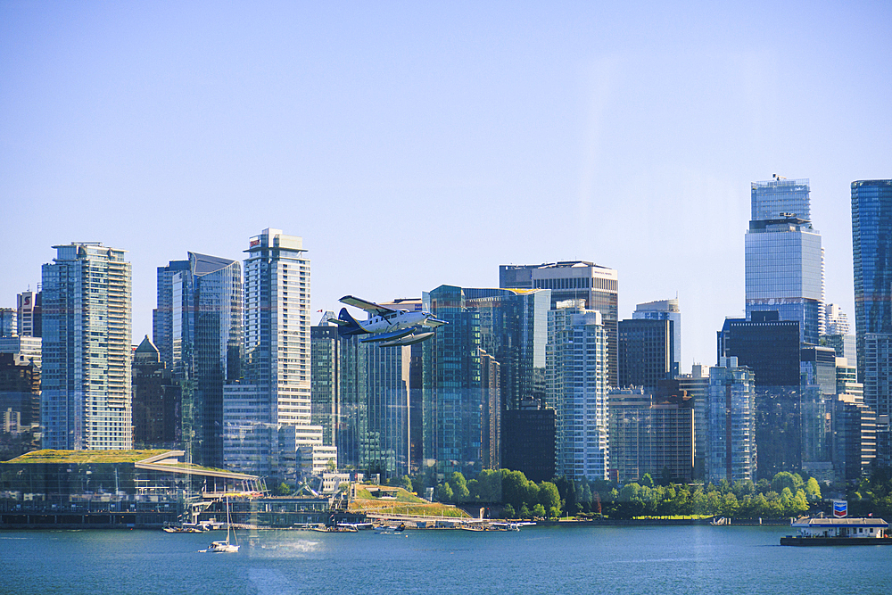 Seaplane flying above Burrard Inlet, downtown buildings in background