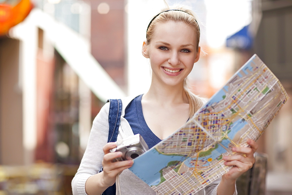 USA, Seattle, Smiling young woman holding map