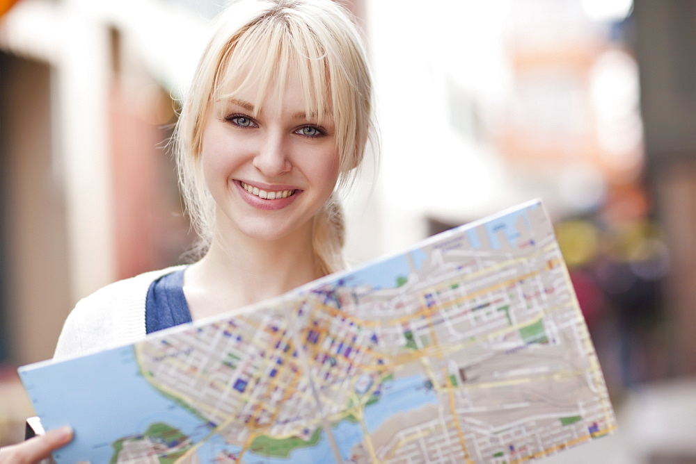 USA, Seattle, Smiling young woman holding map