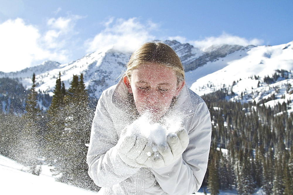 Girl (10-11) blowing snow in mountains