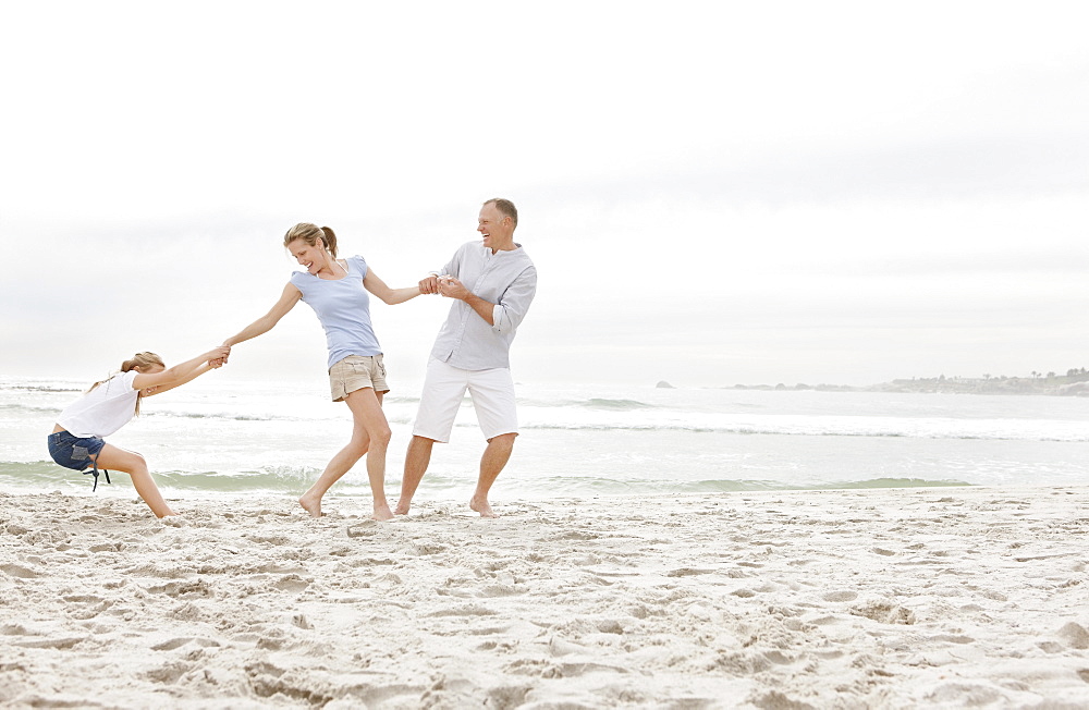 Girl (10-11) playing on beach with parents