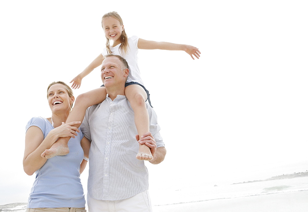 Girl (10-11) playing on beach with parents