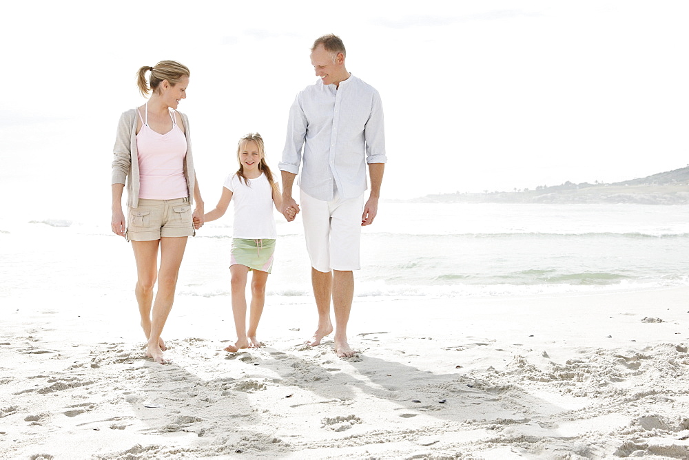 Girl (10-11) playing on beach with parents