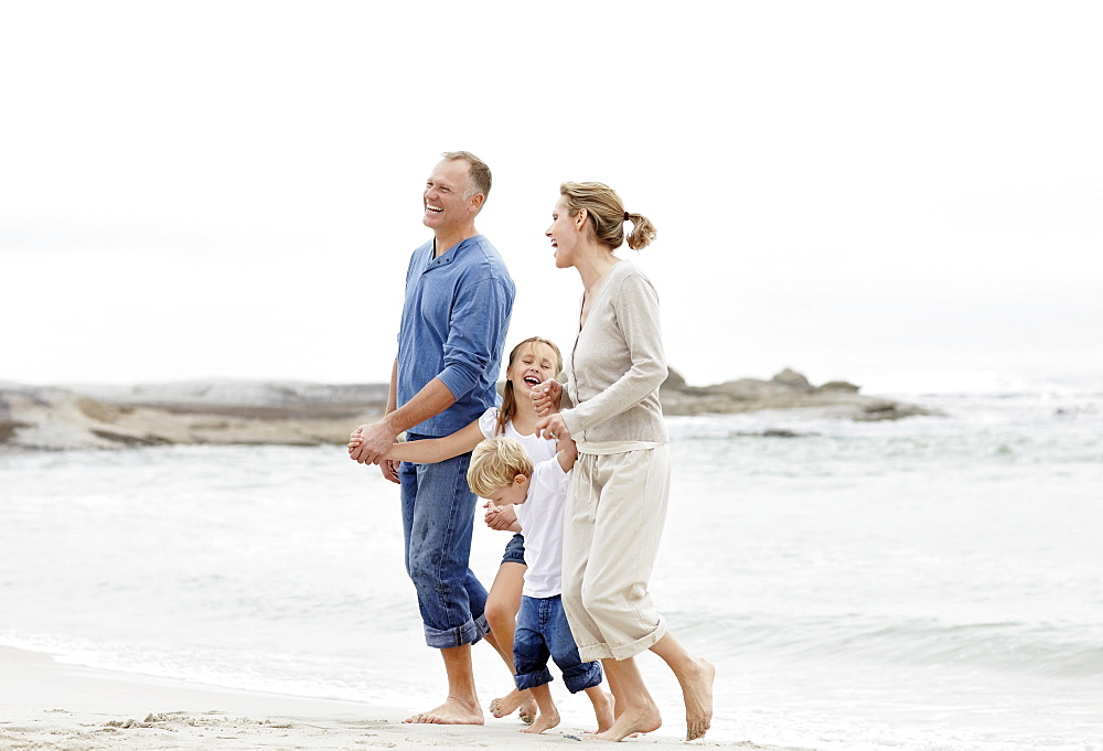 Girl (10-11) and boy (4-5) playing on beach with parents