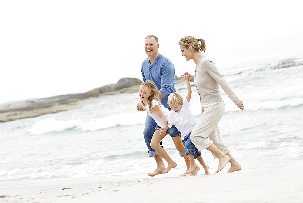 Girl (10-11) and boy (4-5) playing on beach with parents