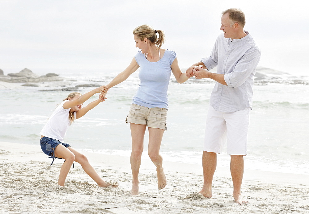 Girl (10-11) playing on beach with parents