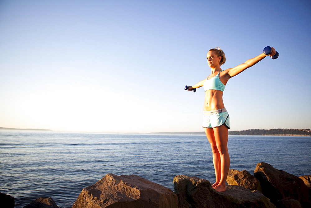 Athletic woman lifting weights outdoors