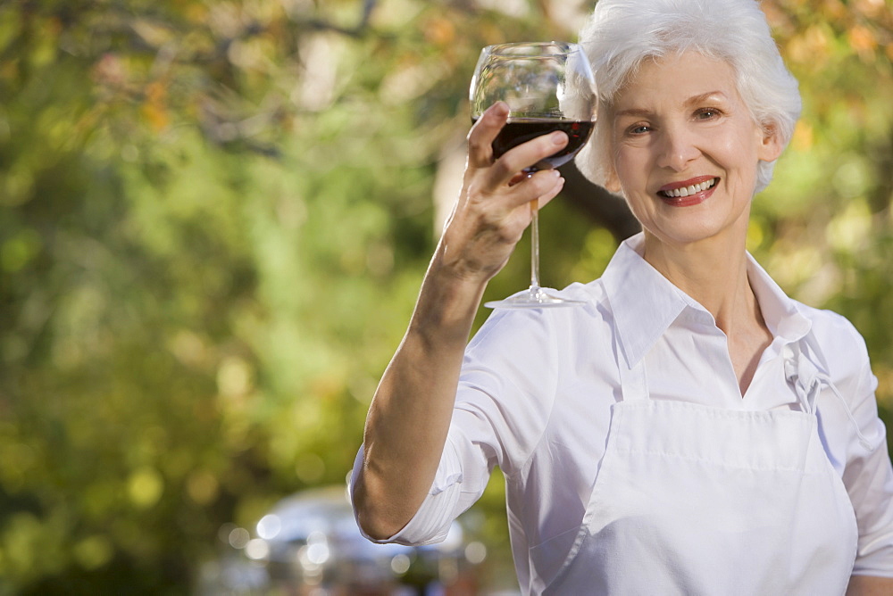 Senior woman holding glass of red wine, portrait