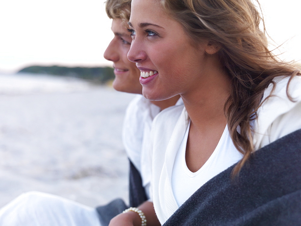 Young couple wrapped in blankets on beach