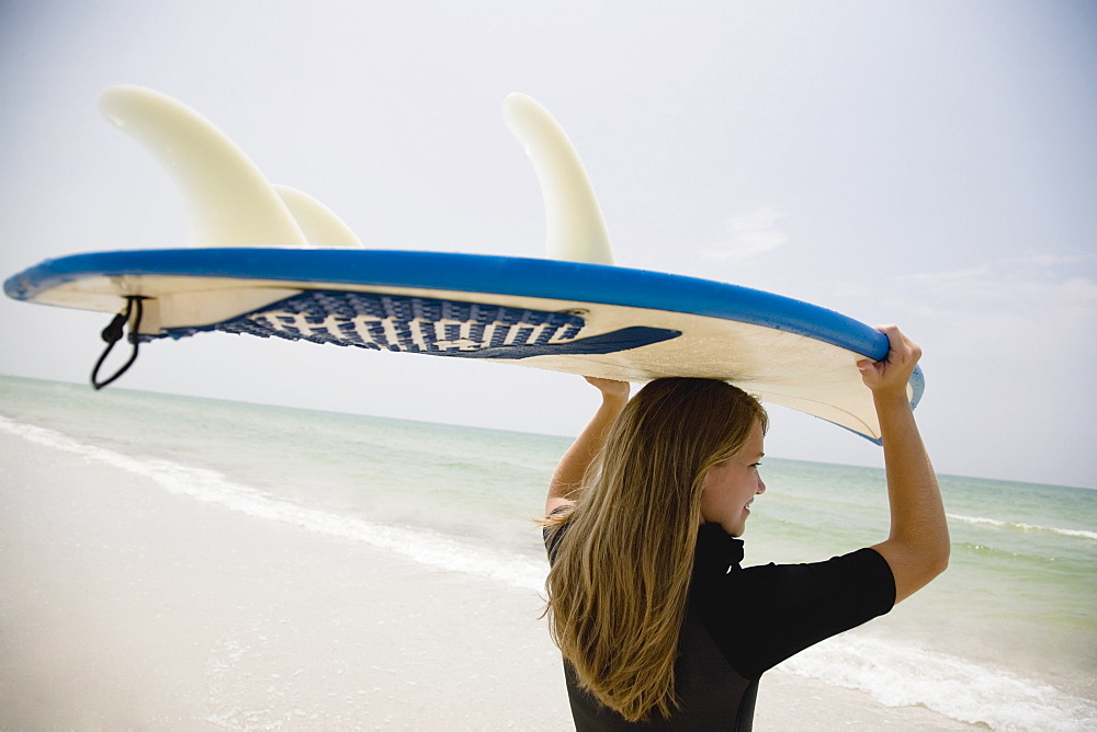 Girl holding surfboard on head, Florida, United States