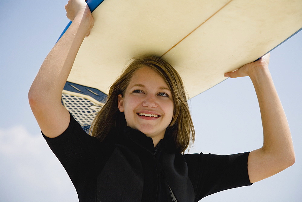 Girl holding surfboard on head, Florida, United States