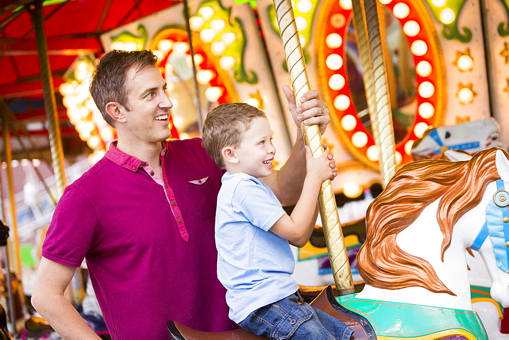 Father and son (4-5) on carousel in amusement park, USA, Utah, Salt Lake City 