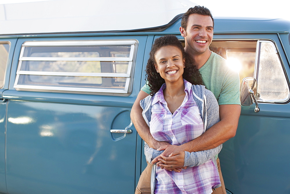 Young couple in front of mini van during road trip