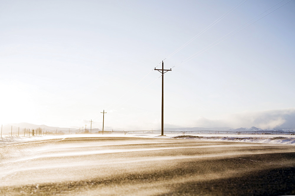 Snow blowing across rural road, Colorado, USA