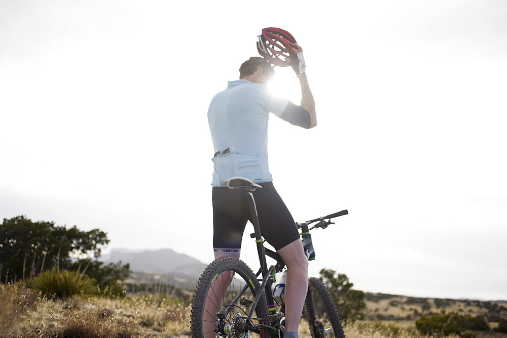 Man on mountain bike fixing helmet, Colorado, USA