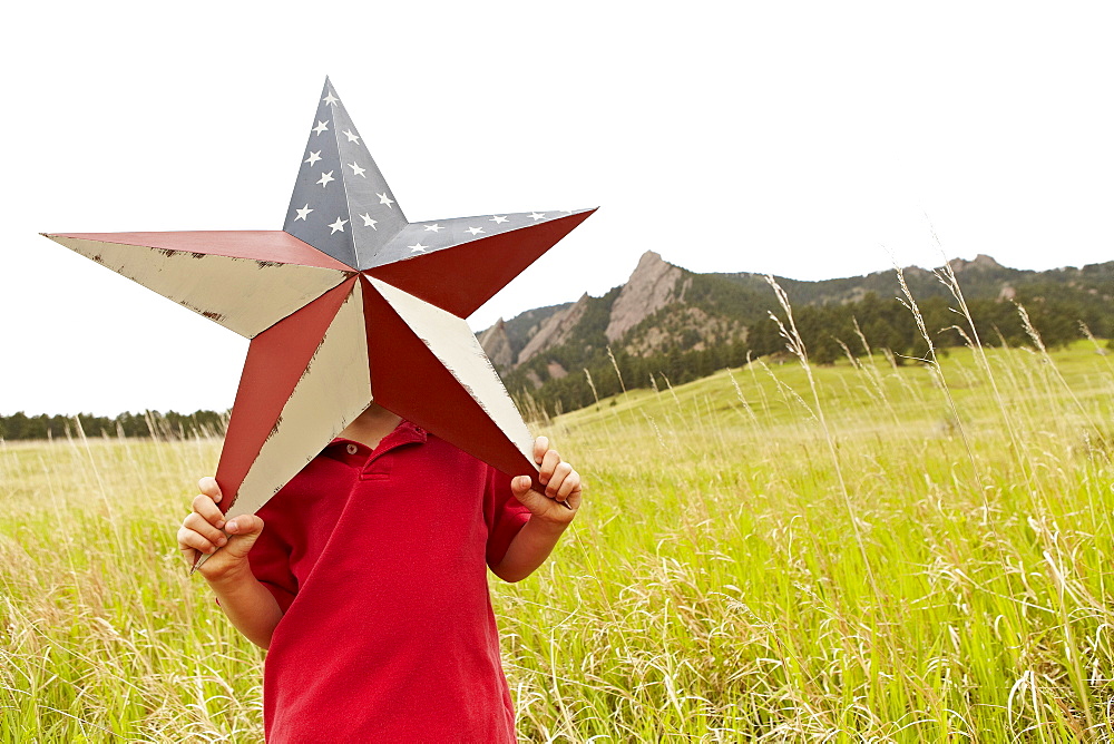 Boy (6-7) playing with star with American flag pattern