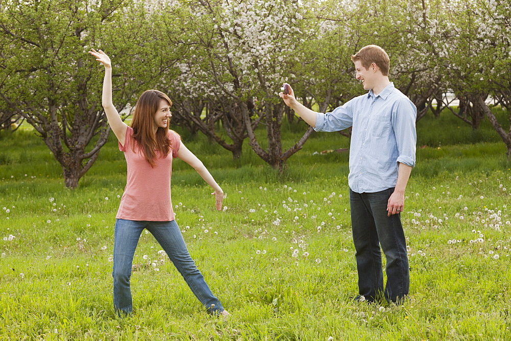 USA, Utah, Provo, Young man photographing young woman in orchard