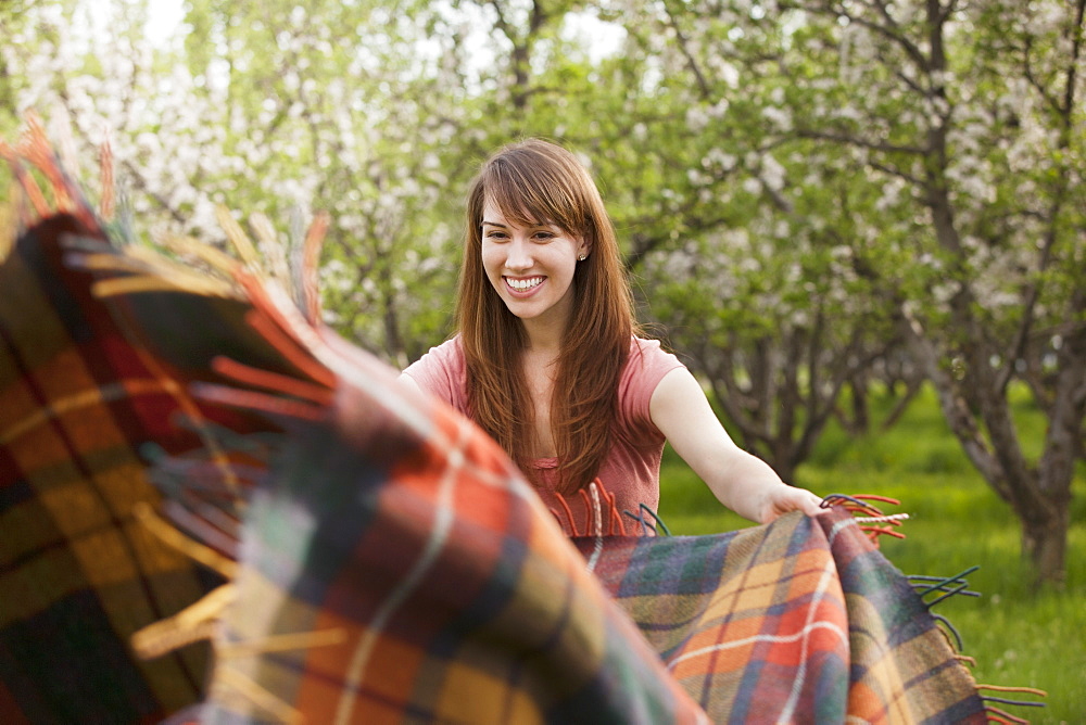 Young woman holding blanket in orchard