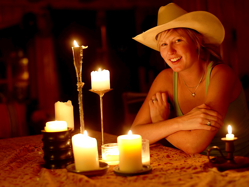USA, Colorado, Portrait of cowgirl sitting at table with candles