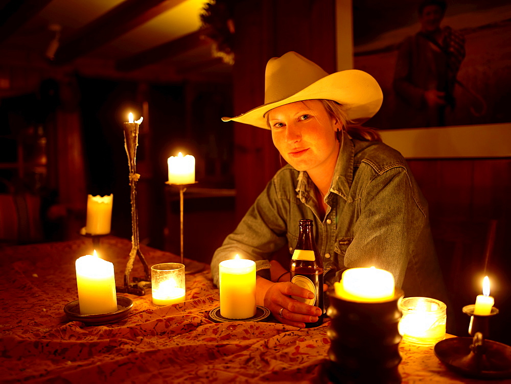 USA, Colorado, Portrait of cowgirl sitting at table with candles