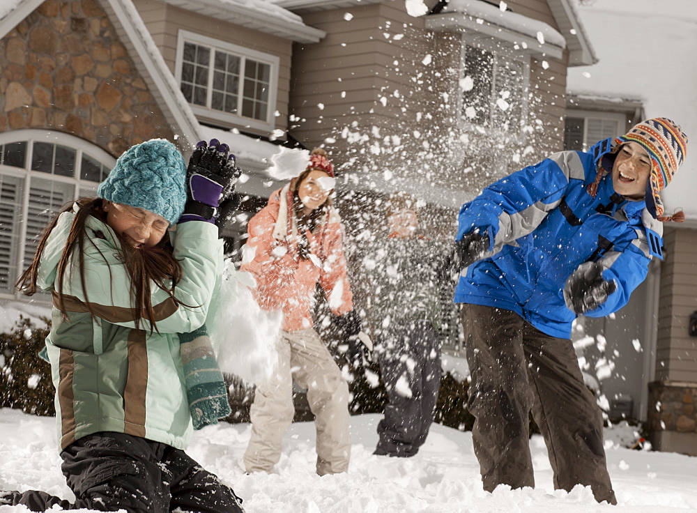 USA, Utah, Provo, Boys (10-11, 12-13) and girls (10-11, 16-17) having snow ball fight in front of house