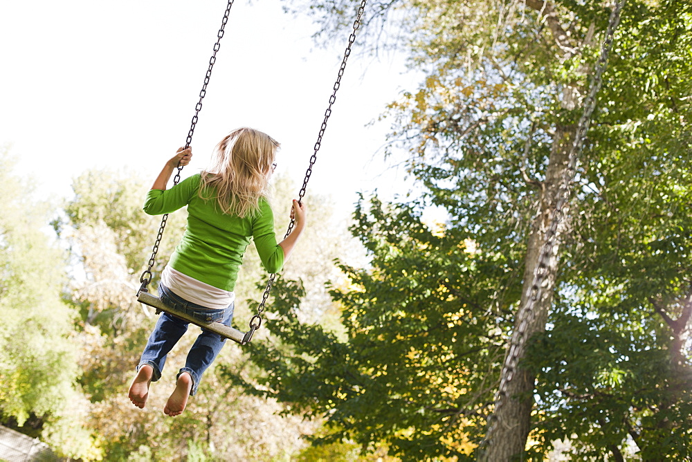 USA, Utah, girl (6-7) swinging on tree swing