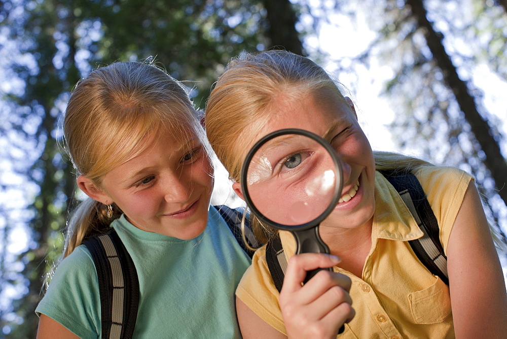 Canada, British Columbia, Fernie, sisters looking through magnifying glass