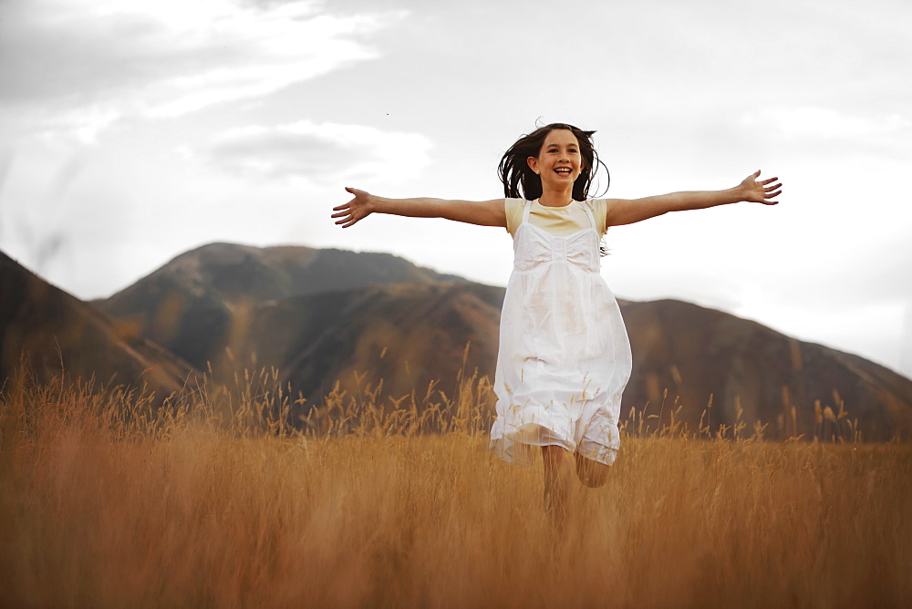 Girl (10-11) running through wheat field