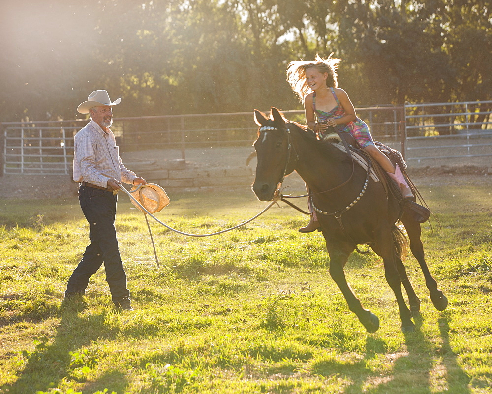 Trainer assisting girl (8-9) riding horse in paddock