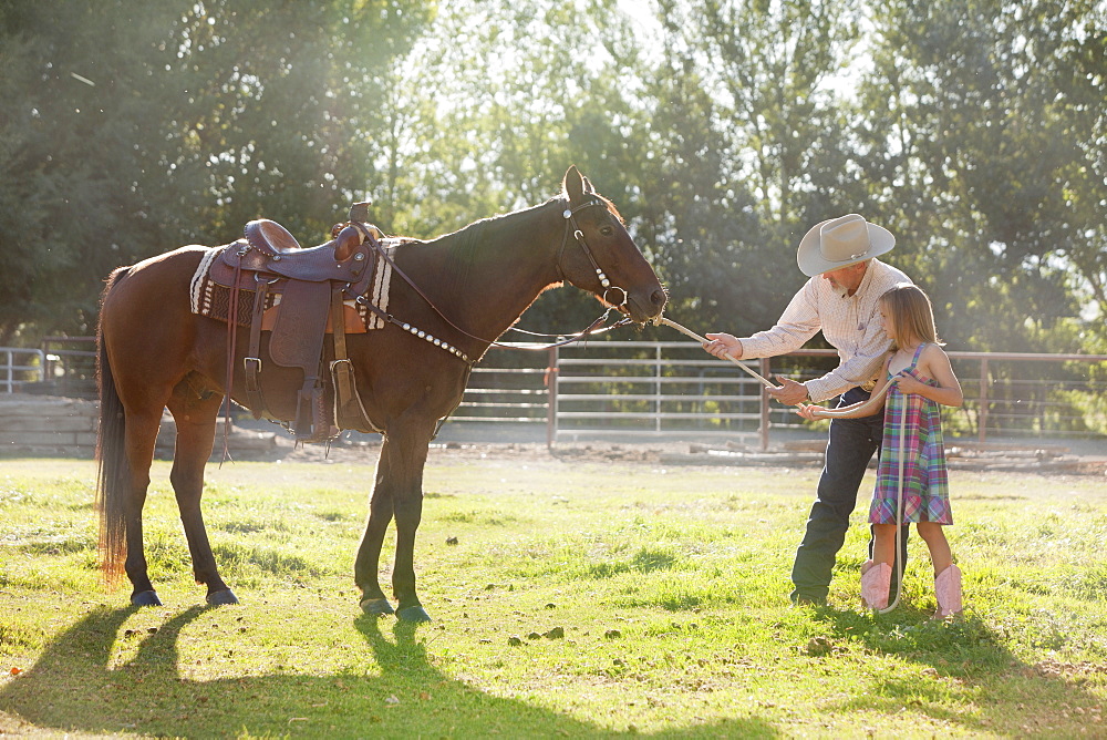 Senior man with granddaughter (8-9) training horse in ranch