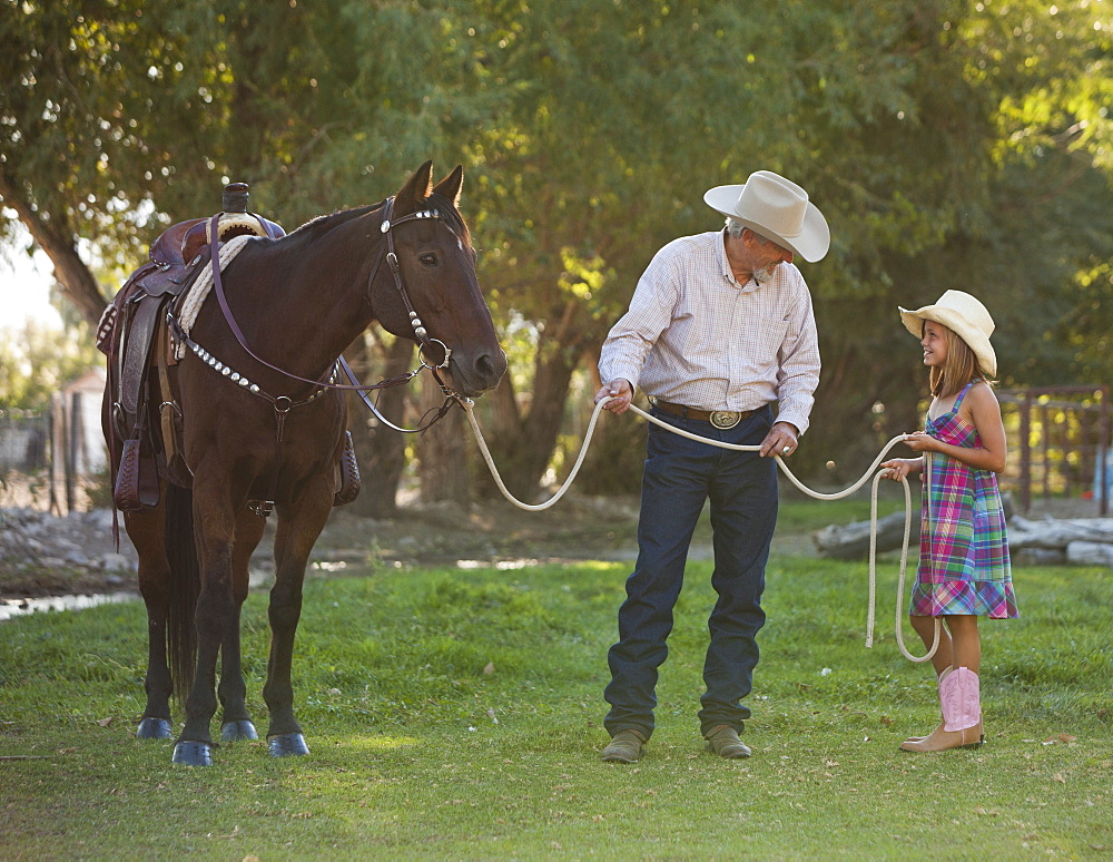 Senior man with granddaughter (8-9) training horse in ranch