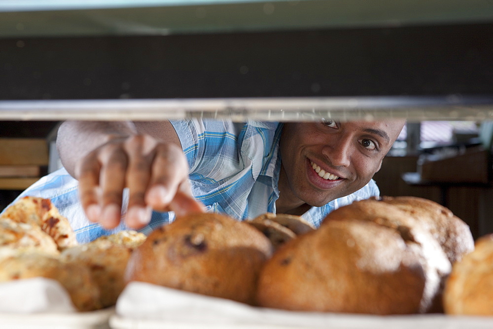 Man reaching for muffin in bakery