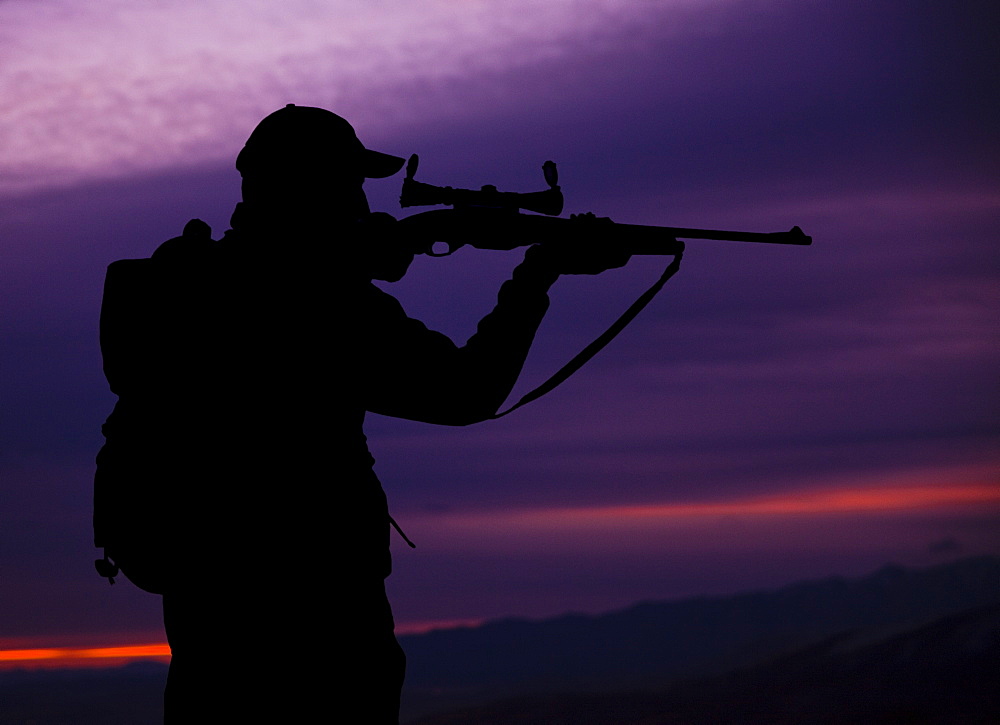 Hunter looking through scope of rifle