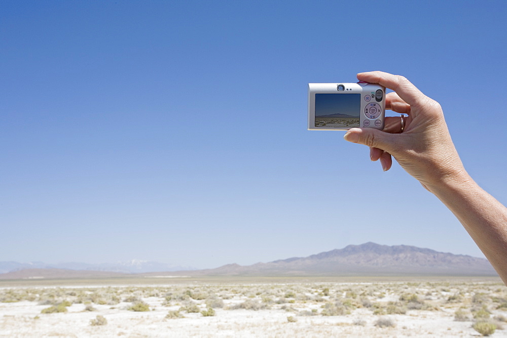 Hand holding a camera in the desert