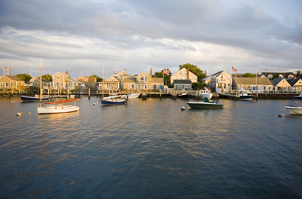 Boats in harbor with village in background