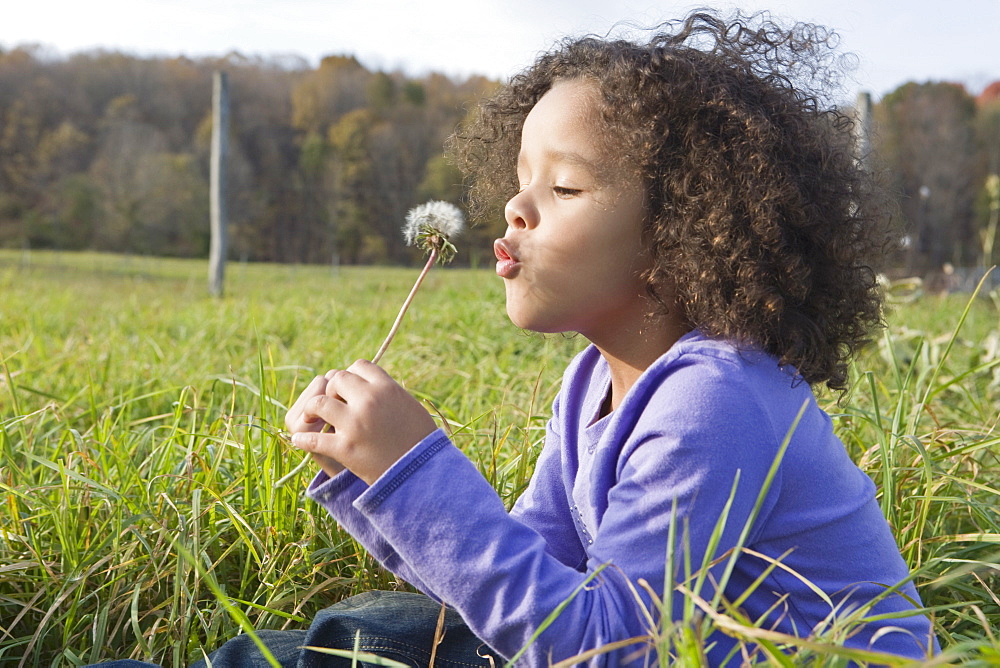 Young girl blowing dandelion