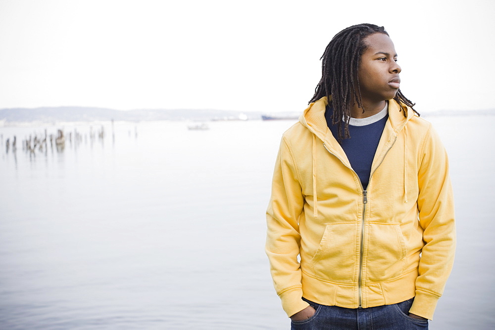 Teenage boy (16-17) with dreadlocks, standing at waterfront, San Francisco, California, USA