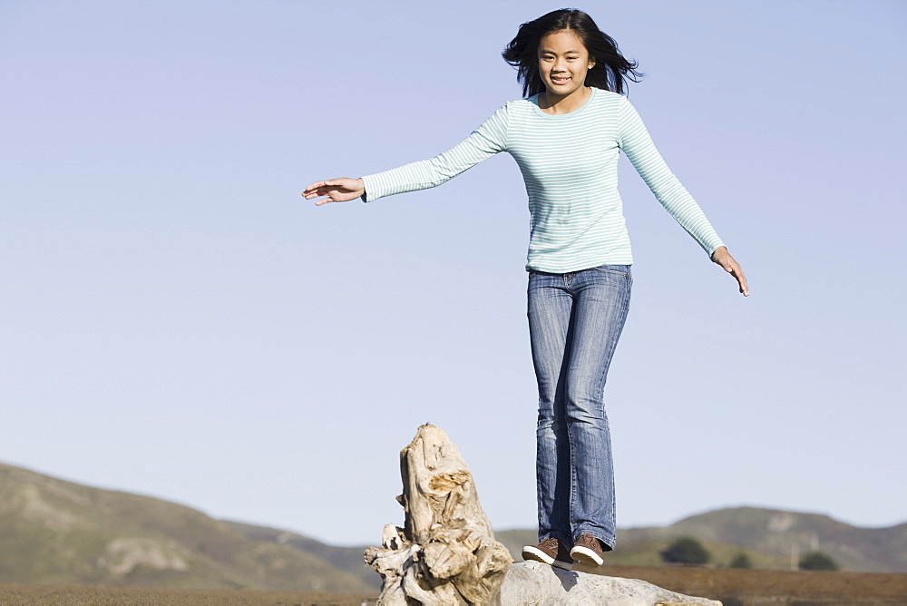 Teenage girl balancing on driftwood