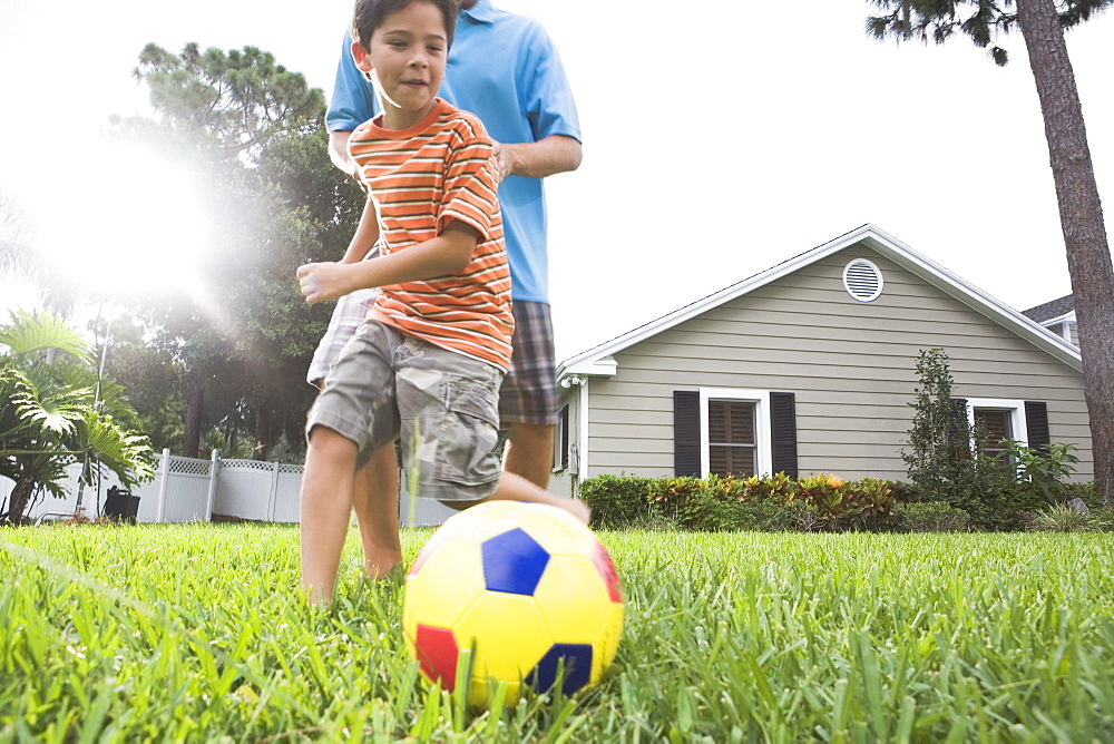 Father and son playing soccer in backyard