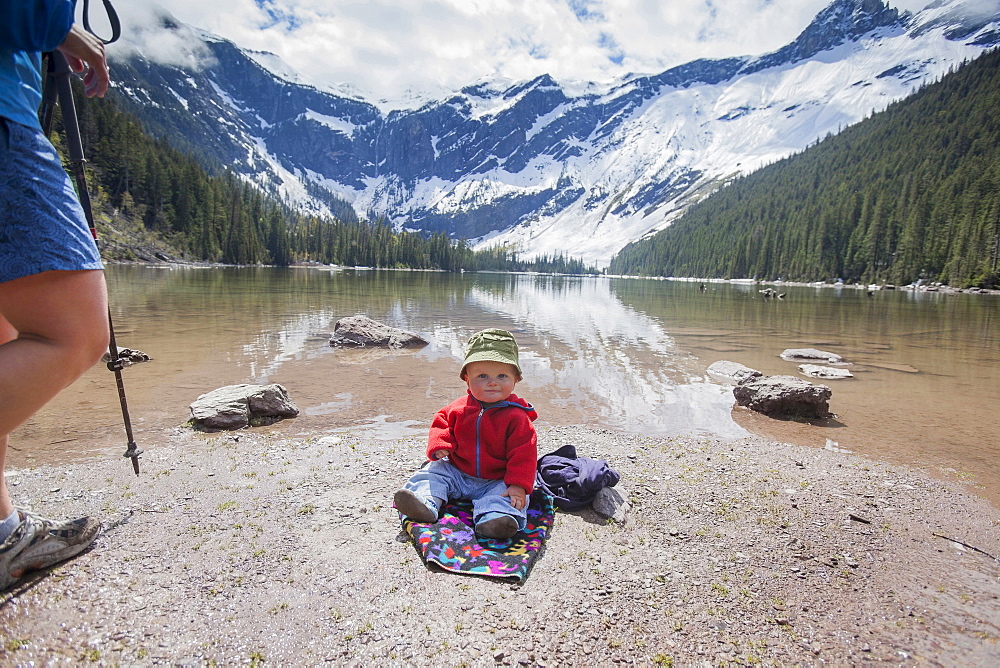 Boy (4-5) sitting on lakeshore, Avalanche Lake, Glacier National Park, Montana, USA