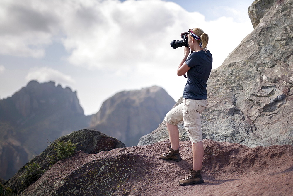 Woman photographing in mountains, Big Bend National Park, Texas, USA
