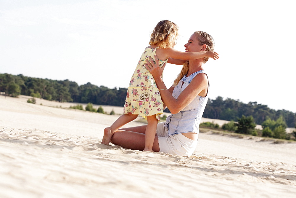 Mother playing with daughter (2-3) at sandy beach, Nationaal Park De Loonse en Drunense Duinen, The Netherlands