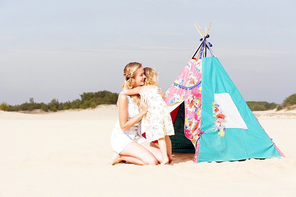 Mother hugging daughter (2-3) on beach, Nationaal Park De Loonse en Drunense Duinen, The Netherlands