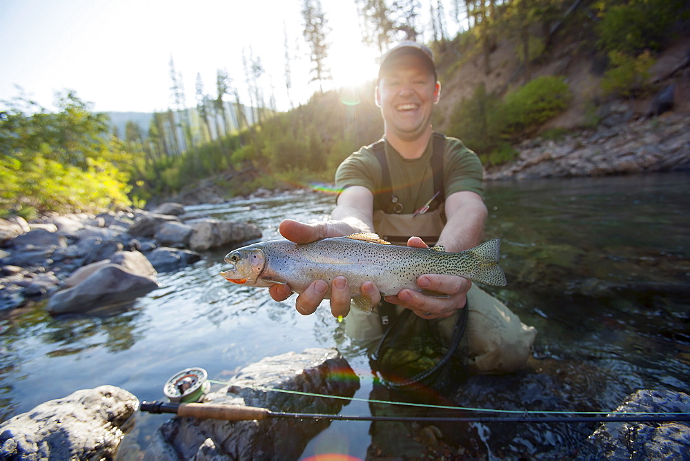 Fisherman showing fresh trout, North Fork Blackfoot River, Montana, USA