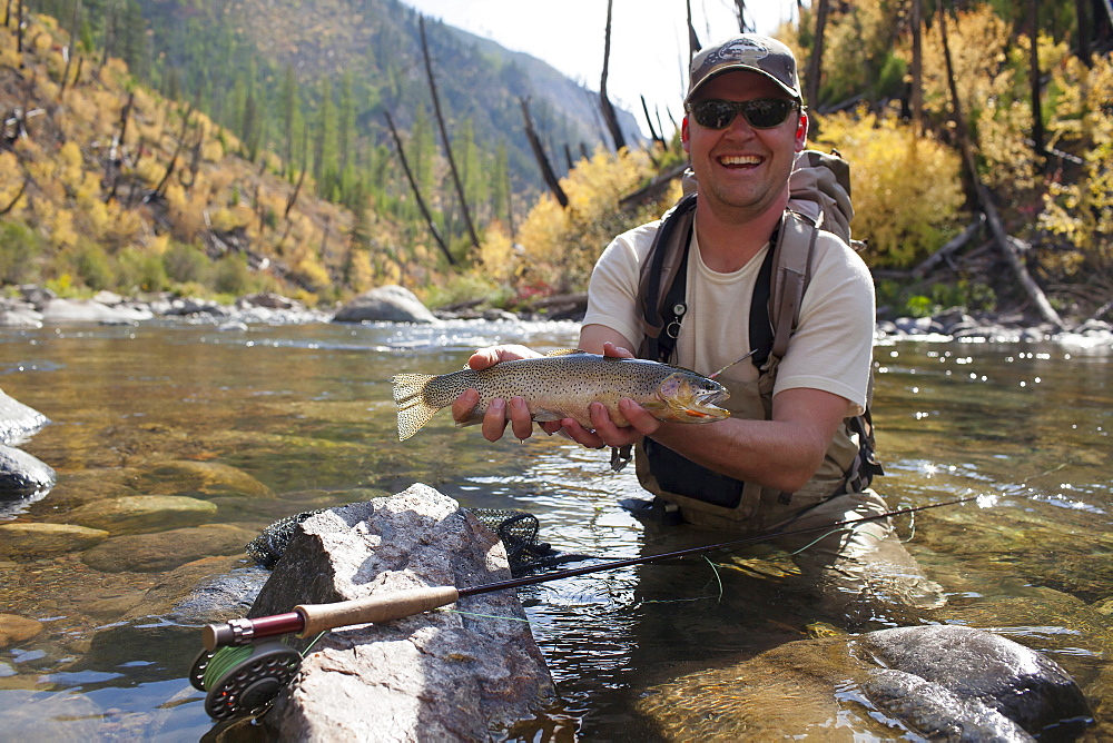 Fisherman showing fresh trout, North Fork Blackfoot River, Montana, USA